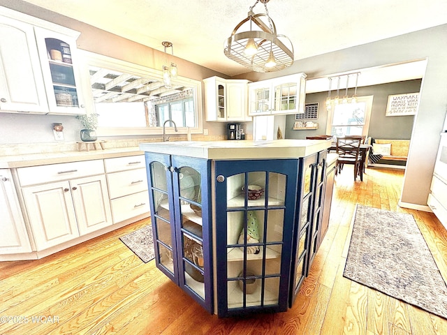 kitchen featuring white cabinetry, a kitchen island, pendant lighting, and light wood-type flooring