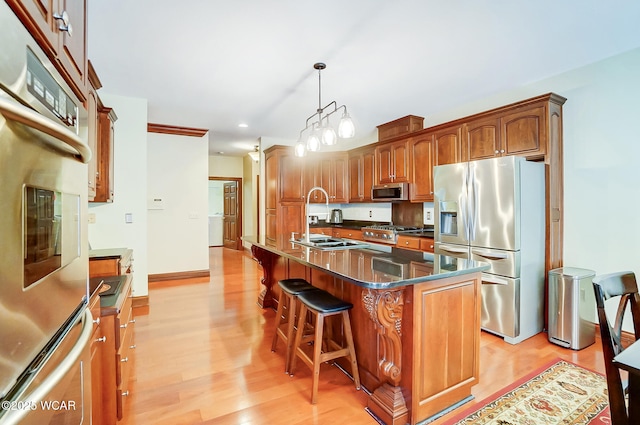 kitchen with a kitchen island, appliances with stainless steel finishes, pendant lighting, sink, and a kitchen breakfast bar