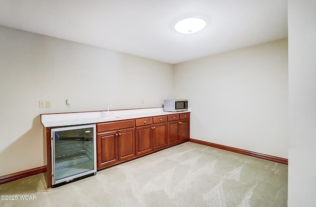 bar with sink, light colored carpet, and beverage cooler