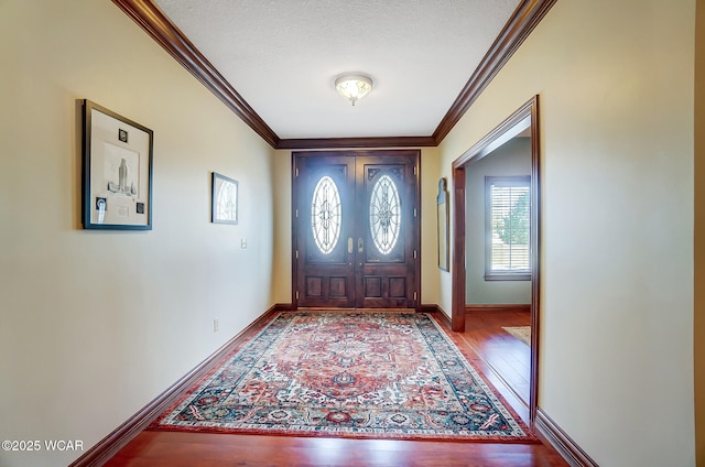 foyer with ornamental molding, a textured ceiling, and light wood-type flooring