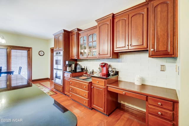 kitchen featuring tasteful backsplash, double oven, light hardwood / wood-style floors, and stovetop