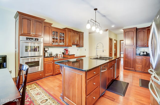 kitchen with sink, a center island, light wood-type flooring, pendant lighting, and stainless steel appliances