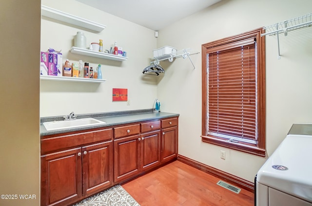 laundry room featuring washer / dryer, sink, and light hardwood / wood-style flooring