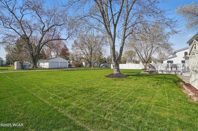 view of yard with an outdoor structure, fence, a garage, a wooden deck, and a residential view