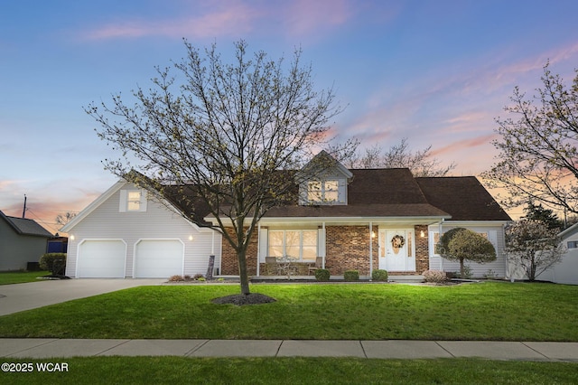 view of front of property featuring brick siding, a porch, a front yard, and concrete driveway
