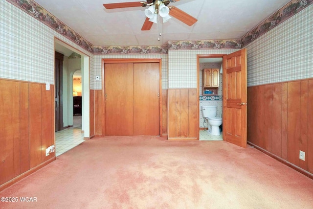 315 W Main St, Cairo, OH 45820 - unfurnished bedroom featuring wallpapered walls, wainscoting, arched walkways, wood walls, and carpet floors