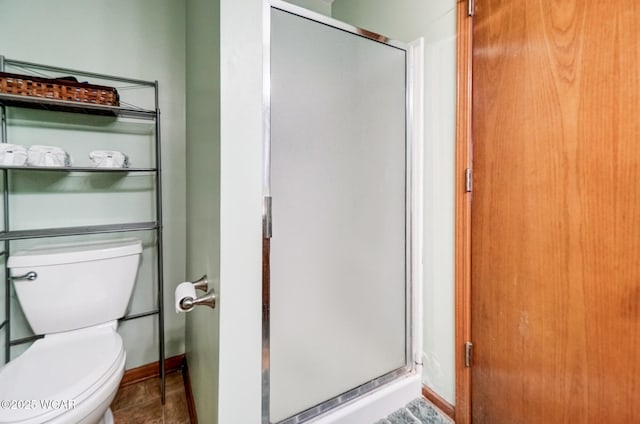 full bathroom with a stall shower, toilet, and baseboards