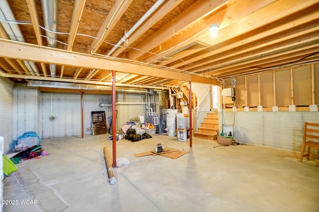 unfinished basement with stairway and electric water heater