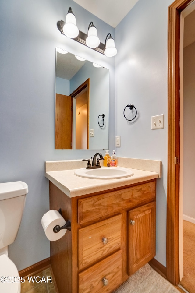 bathroom with baseboards, toilet, and vanity
