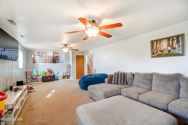 living room with visible vents, ceiling fan, carpet flooring, and stairway
