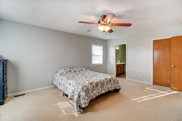 carpeted bedroom featuring visible vents, a ceiling fan, ensuite bathroom, and baseboards