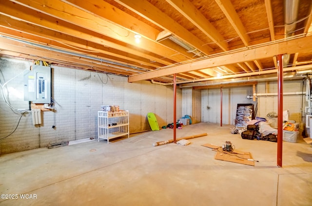 unfinished below grade area featuring electric panel and brick wall