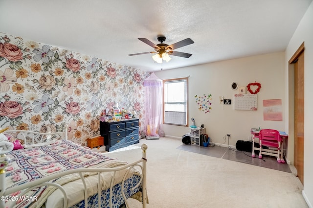 bedroom with wallpapered walls, ceiling fan, baseboards, carpet floors, and a textured ceiling