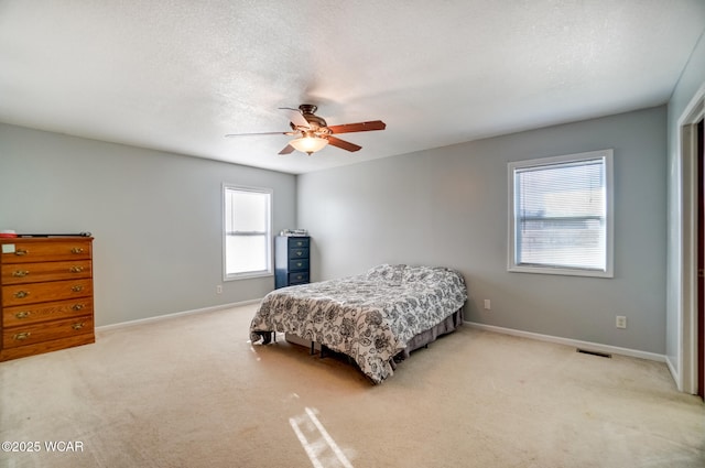 bedroom featuring light carpet, a textured ceiling, baseboards, and a ceiling fan