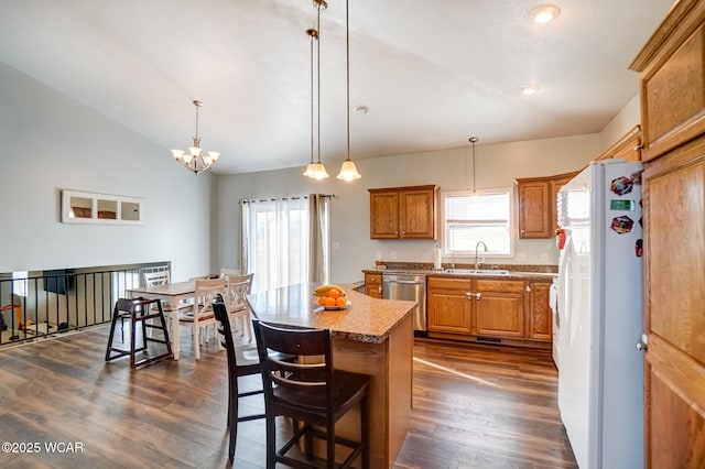kitchen featuring brown cabinetry, stainless steel dishwasher, freestanding refrigerator, dark wood-style floors, and a sink