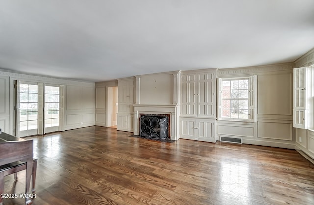 unfurnished living room featuring a healthy amount of sunlight and dark hardwood / wood-style flooring