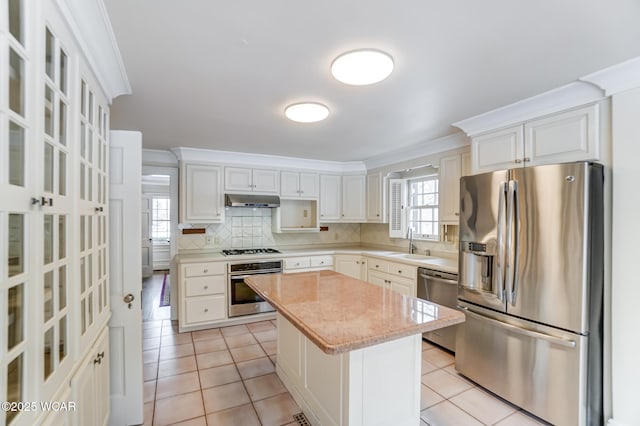 kitchen with white cabinets, stainless steel appliances, a kitchen island, and backsplash