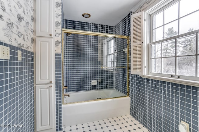 bathroom featuring bath / shower combo with glass door, plenty of natural light, tile walls, and tile patterned floors