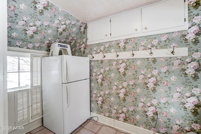 kitchen with white cabinetry, light tile patterned floors, and white fridge