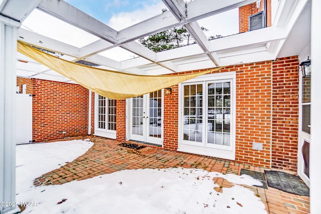 snow covered patio with a pergola and french doors