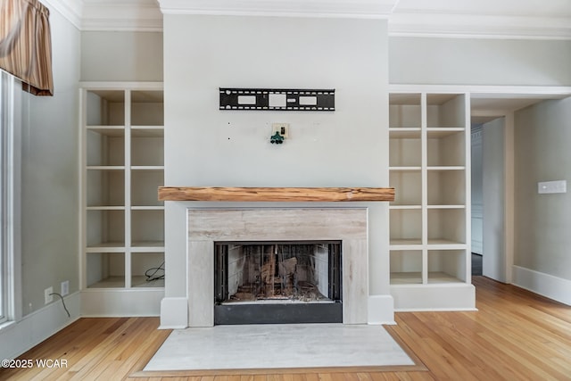 interior details with ornamental molding, wood-type flooring, and a high end fireplace