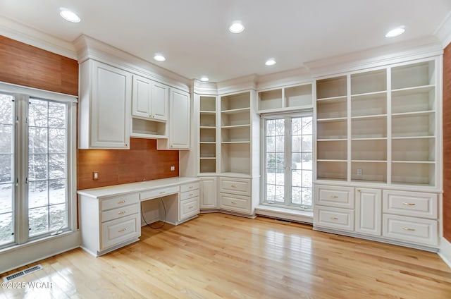 unfurnished office with a wealth of natural light, built in desk, and light wood-type flooring