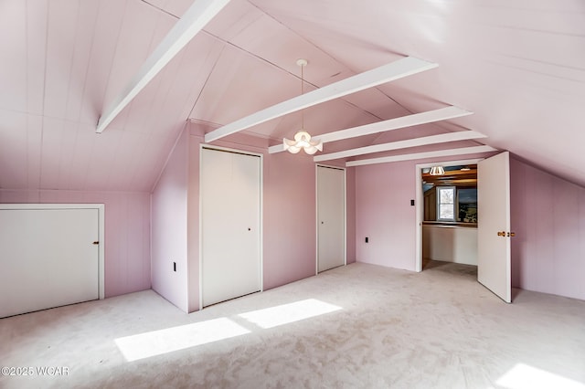 bonus room with lofted ceiling with beams and light carpet