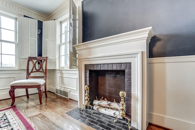 living area with hardwood / wood-style floors, a fireplace, and ornamental molding