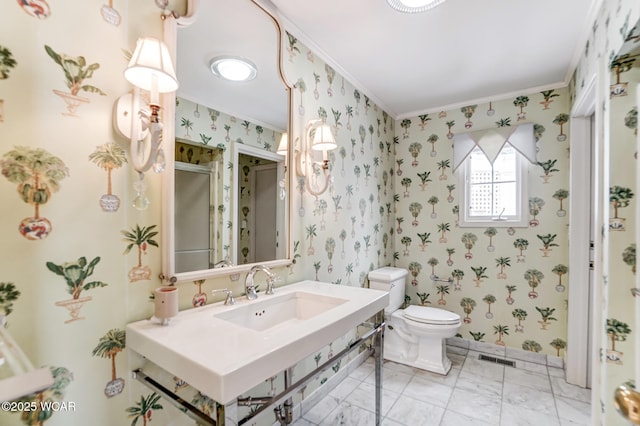 bathroom featuring sink, ornamental molding, toilet, and walk in shower