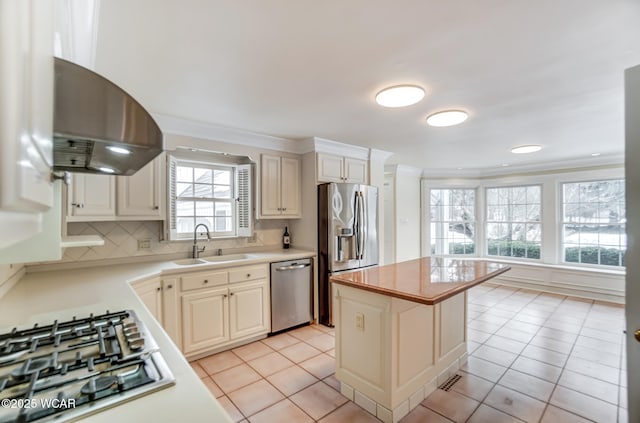 kitchen with sink, a center island, light tile patterned floors, appliances with stainless steel finishes, and exhaust hood