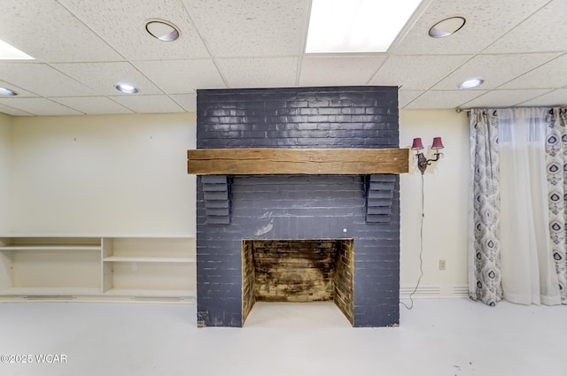 interior space featuring concrete flooring, a brick fireplace, and a paneled ceiling