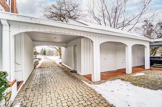 snow covered garage with a carport