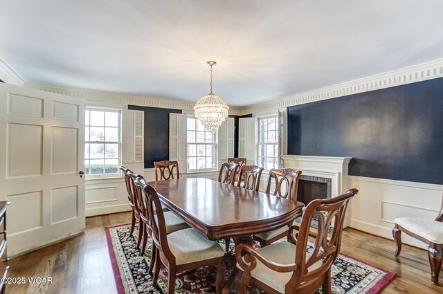 dining space with crown molding, a notable chandelier, a fireplace, and light hardwood / wood-style flooring