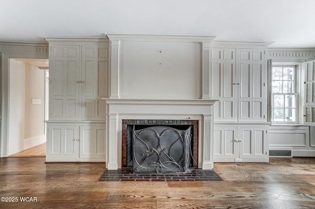 interior space with wood-type flooring, a brick fireplace, and crown molding