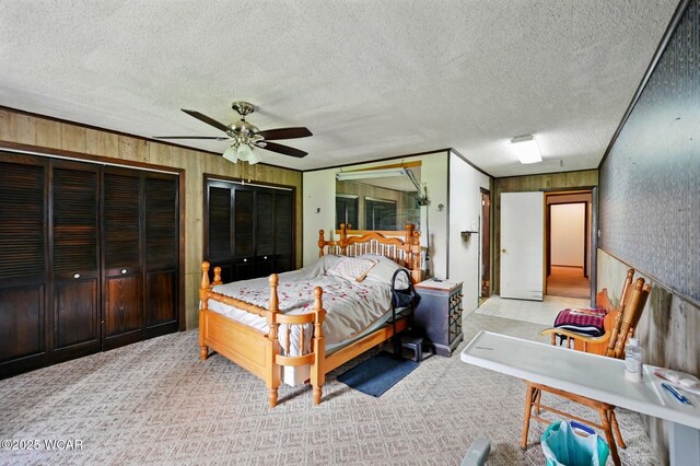 1398 Lutz Rd, Lima, OH 45801 - bedroom featuring carpet flooring, a textured ceiling, wood walls, a ceiling fan, and two closets
