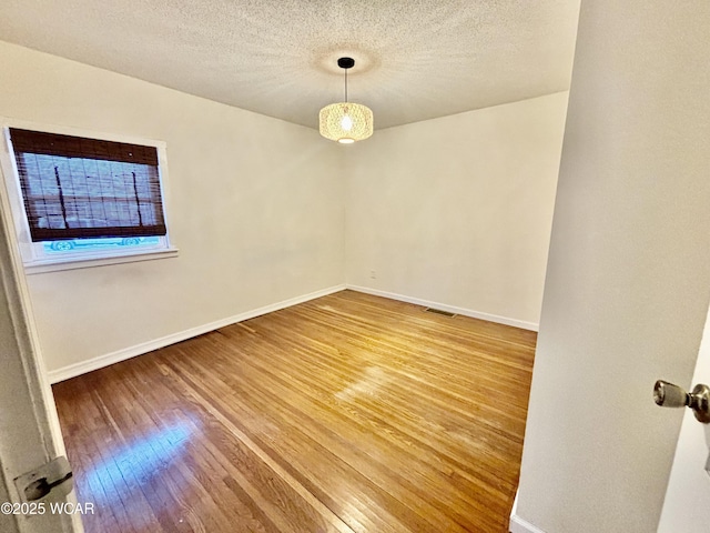 unfurnished room featuring hardwood / wood-style floors and a textured ceiling