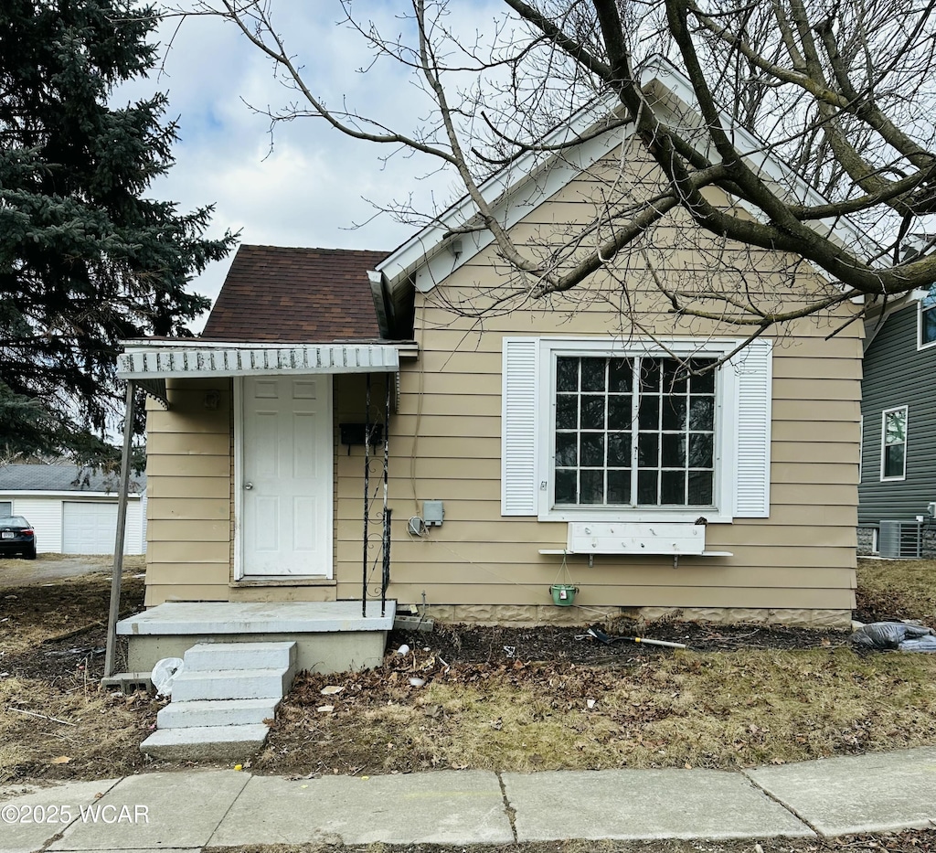 bungalow-style home featuring a shingled roof and central AC