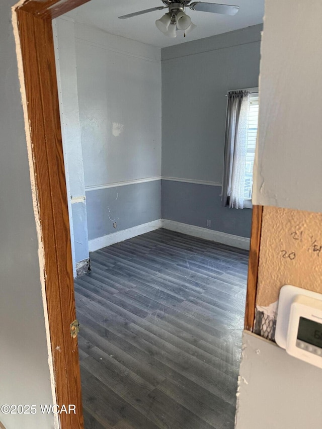 empty room featuring heating unit, baseboards, a ceiling fan, and wood finished floors