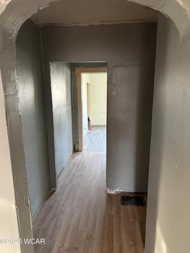 hallway featuring wood finished floors and arched walkways