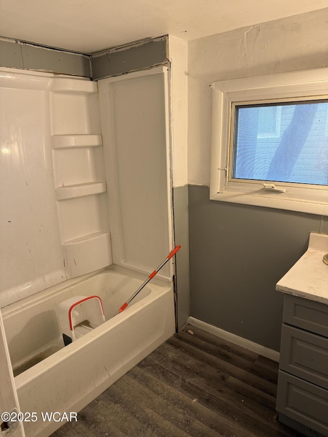 full bathroom featuring wood finished floors, vanity, bathing tub / shower combination, and baseboards
