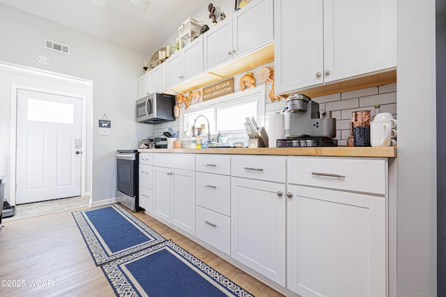127 Brads Way, Russells Point, OH 43348 - kitchen with appliances with stainless steel finishes, backsplash, white cabinets, and light wood-type flooring