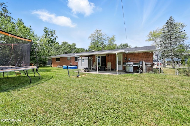 2238 N Glenwood Ave, Lima, OH 45805 - rear view of property with a trampoline, a patio, and brick siding