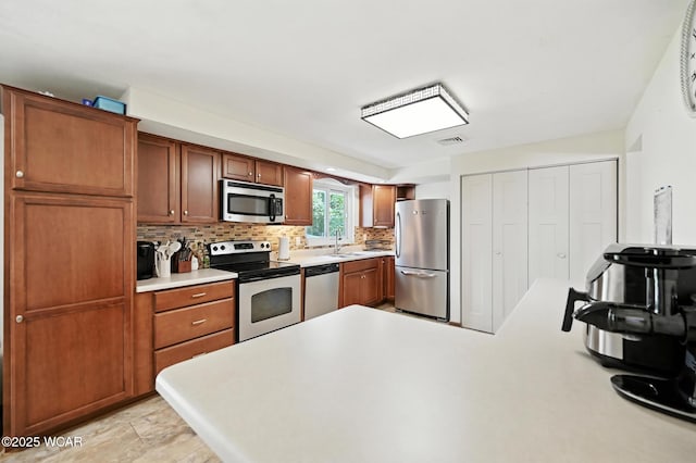 2238 N Glenwood Ave, Lima, OH 45805 - kitchen with appliances with stainless steel finishes, light countertops, tasteful backsplash, brown cabinetry, and a peninsula