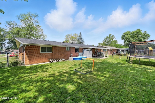 2238 N Glenwood Ave, Lima, OH 45805 - rear view of house featuring a trampoline, brick siding, a storage unit, a fenced backyard, and a gate