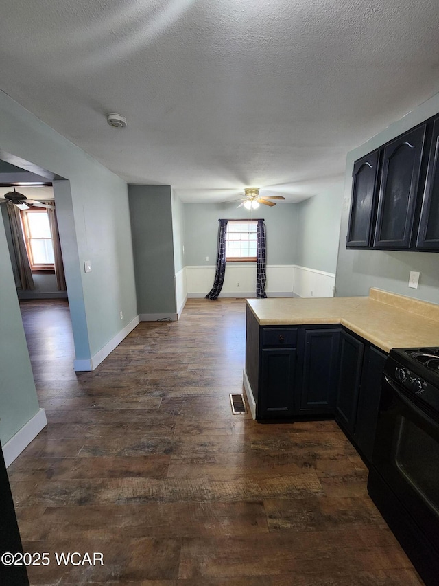 kitchen featuring a textured ceiling, dark hardwood / wood-style floors, black range, kitchen peninsula, and ceiling fan