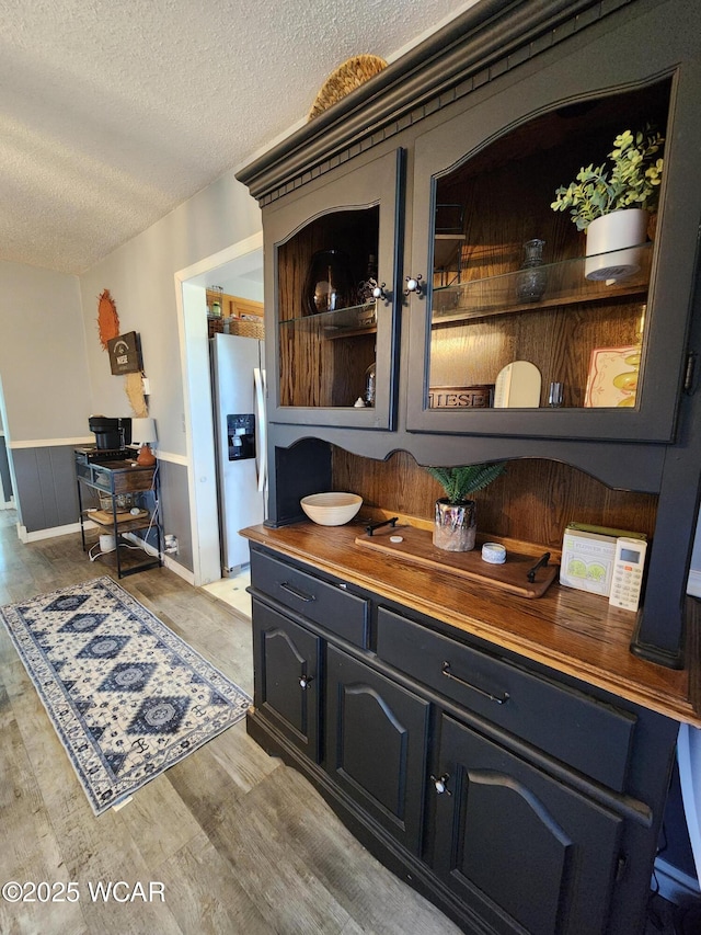 kitchen featuring open shelves, light wood-style flooring, stainless steel fridge, and a textured ceiling