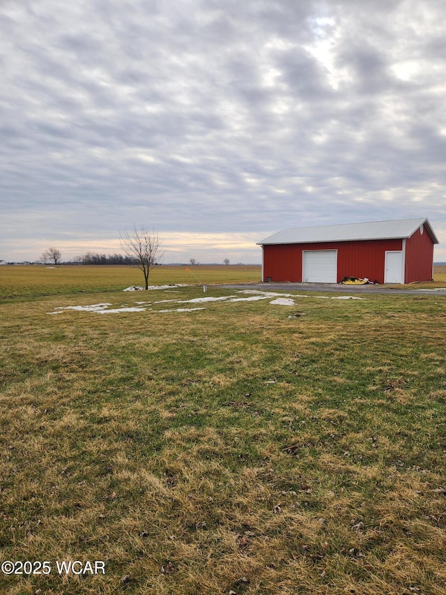 view of yard featuring a rural view, a garage, and an outdoor structure