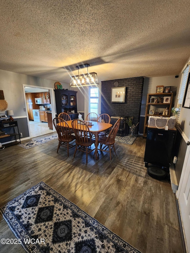 dining space with a textured ceiling and dark wood-style flooring