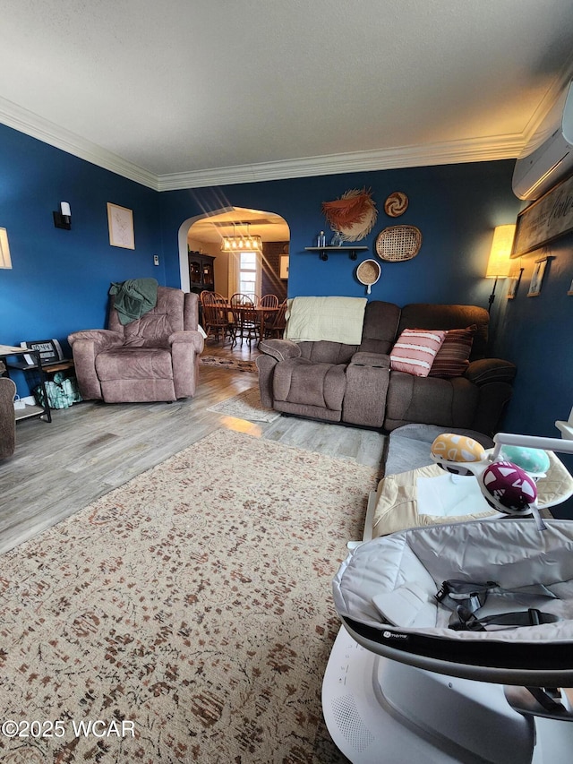 living room with arched walkways, wood finished floors, a wall unit AC, and crown molding