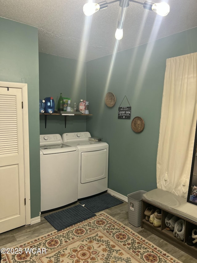 clothes washing area with hardwood / wood-style floors, washing machine and dryer, and a textured ceiling